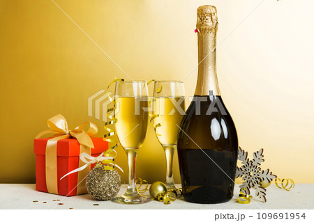 Champagne bottle with confetti, glasses and christmas decor on colored holiday background. Flat lay New Year decorations 109691954