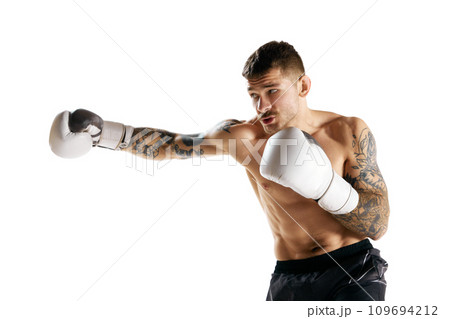 Young muscular man, boxer in motion, training isolated over white background. Male model practicing shirtless Young muscular man, boxer in motion, training isolated over white background. Male model practicing shirtless 109694212