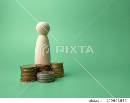 Wooden people figures and coins on a green background with copy space. 109698656