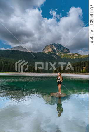 Woman Solo Traveler Standing in Black Lake Woman Solo Traveler Standing in Black Lake 109699652