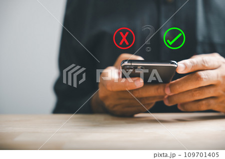 Using smartphones businessman reveals right and wrong icons for yes or no decision-making. Communication of choice and expertise. Think With Yes Or No Choice. 109701405