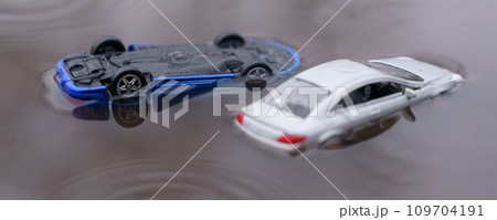 Two cars were flooded, one overturned as a result of the flood. One of them is out of focus. 109704191