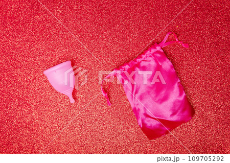 menstrual cup with satin pouch on shiny red background, top view. Zero waste concept. Eco-friendly menstrual products menstrual cup with satin pouch on shiny red background, top view. Zero waste concept. Eco-friendly menstrual products 109705292