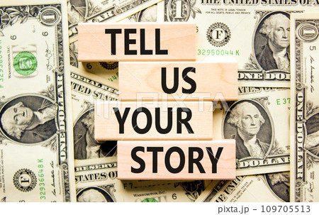 Tell us your story symbol. Concept word Tell us your story on beautiful wooden block. Dollar bills. Beautiful background from dollar bills. Business tell us your story concept. Copy space. 109705513