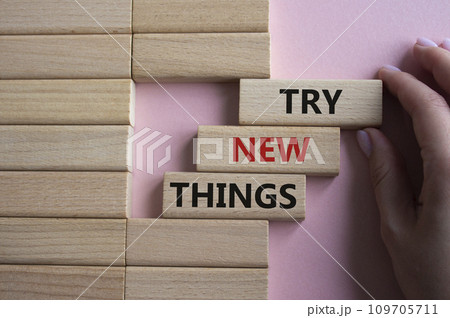Try new Things symbol. Concept words Try new Things on wooden blocks. Businessman hand. Beautiful pink background. Business and Try new Things concept. Copy space. 109705711