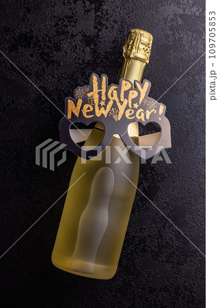 Happy new year background. Black funny paper glasses and bottle of champagne on black table. Top view. Happy new year background. Black funny paper glasses and bottle of champagne on black table. Top view. 109705853