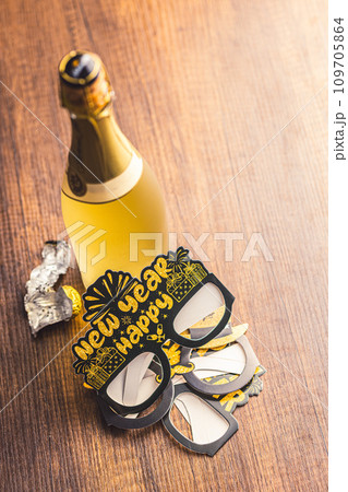 Happy new year background. Black funny paper glasses and bottle of champagne on wooden table. Happy new year background. Black funny paper glasses and bottle of champagne on wooden table. 109705864