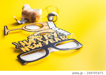 Happy new year background. Black funny paper glasses and bottle of champagne on yellow background. Happy new year background. Black funny paper glasses and bottle of champagne on yellow background. 109705871