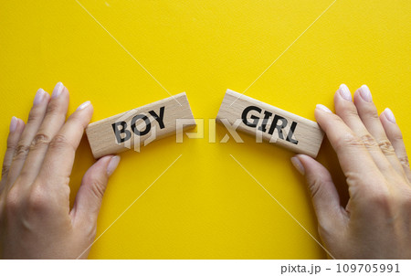 Boy or Girl symbol. Concept word Boy or Girl on wooden blocks. Man hand. Beautiful yellow background. Gender and Boy or Girl concept. Copy space 109705991