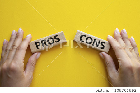 Pros vs Cons symbol. Concept word Pros vs Cons on wooden blocks. Businessman hand. Beautiful yellow background. Business and Pros vs Cons concept. Copy space 109705992
