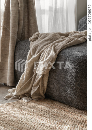 Cozy knitted blanket on a dark grey sofa. Wabi-sabi interior details for decoration Cozy knitted blanket on a dark grey sofa. Wabi-sabi interior details for decoration 109706079