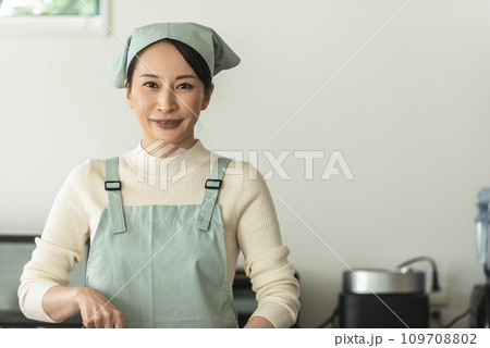 キッチンで料理するエプロン姿の女性 キッチンで料理するエプロン姿の女性 109708802