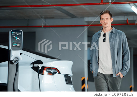 Young man travel with EV electric car to shopping center parking lot innards Young man travel with EV electric car to shopping center parking lot innards 109710218