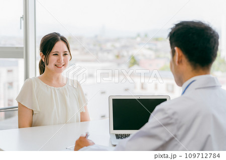 診察を受ける患者の女性と話を聞く医師・医者(早期発見・健康診断・人間ドック・診察・診断・検査) 診察を受ける患者の女性と話を聞く医師・医者(早期発見・健康診断・人間ドック・診察・診断・検査) 109712784