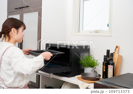 電子レンジを操作する女性　料理　 109713373