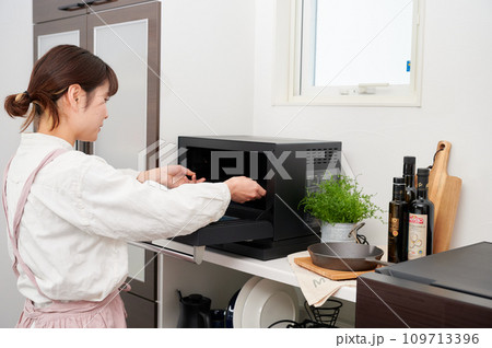 電子レンジを操作する女性　料理　 109713396
