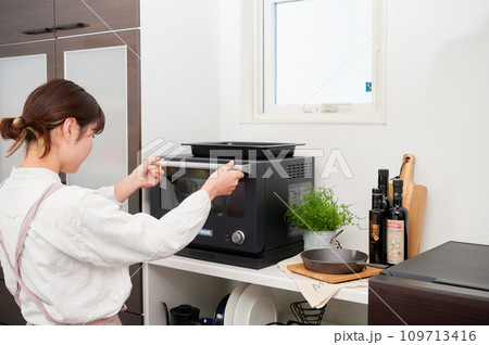 電子レンジを操作する女性　料理　 109713416