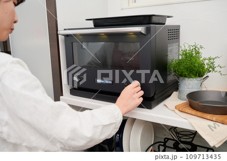 電子レンジをける操作する女性　料理　 109713435