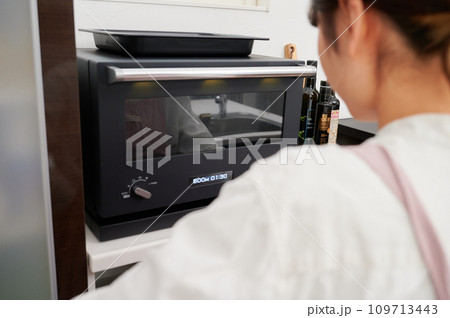 電子レンジを操作する女性　料理　 109713443