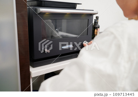 電子レンジを操作する女性　料理　 109713445