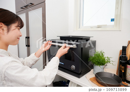 電子レンジを操作する女性　料理　 109713899