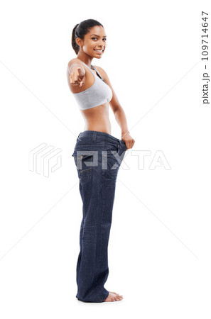 Happy woman, portrait and pointing to lose weight in jeans or decision against a white studio background. Slim female person or model smile for pick or choose in health and wellness on mockup space 109714647