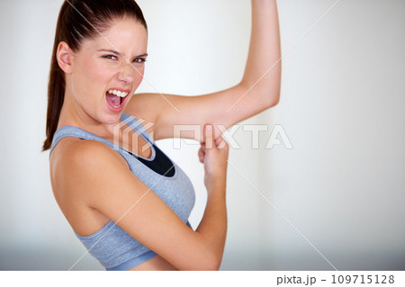 Fitness, arm and woman holding her fat for health, wellness and weight loss goals in a studio. Shout, scream and portrait of young female person showing bicep body for exercise or workout motivation 109715128