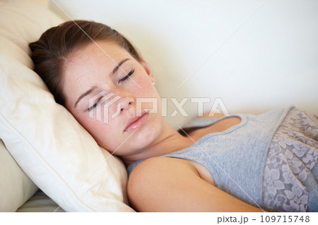 Home, sleeping and relax with woman, tired and resting on a couch, weekend break and peaceful. Person, apartment and girl on a sofa, exhausted and fatigue in a lounge with afternoon nap and dreaming 109715748