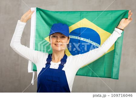 Cheerful female worker with wide grin on her face holding flag of brazil Cheerful female worker with wide grin on her face holding flag of brazil 109716046