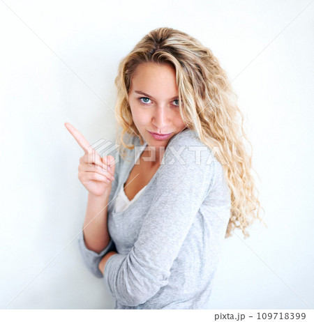 Woman, portrait and pointing finger playful or flirt fun, white wall background as mockup space. Female person, confident and goofy face emoji hand gesture or showing attention, joke humor in Canada 109718399