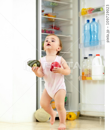 Toddler, little girl and food from fridge in kitchen for running with fresh, fruit and vegetable in hand. Youth, child and curious for organic, natural and nutrition for development of motor skill 109719023
