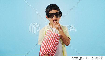Popcorn, 3d or child in studio for a movie, watching tv or VR film on blue background with snack. Future technology, virtual reality experience or kid eating food for 3d cinema or metaverse show 109719084