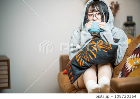 ソファーに座り温かい飲み物を飲む女性 109720364
