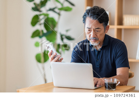 リビングで株式投資をするシニア男性。 109724361