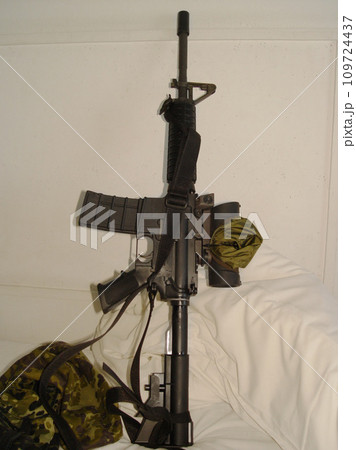 War, camouflage and a rifle on a bed in the home of a soldier ready for conflict, battle or fighting. Army, military or weapon leaning against a wall in an apartment for self defense or patriotism 109724437