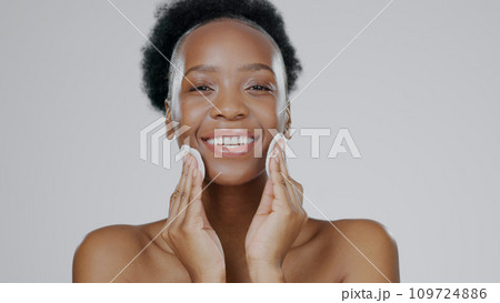 Face, model and hands with cotton for beauty, facial and cosmetic with happiness in studio background. Black woman, healthy skin and dermatology with self care, spa treatment and aesthetic portrait 109724886