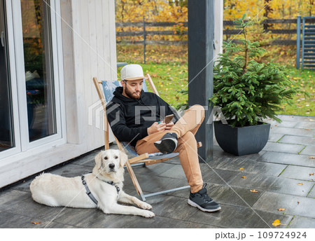 Young man sitting with dog on terrace. 109724924