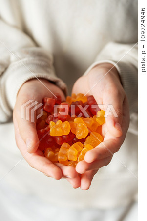 A girl holds a gummy bear vitamines in her hands A girl holds a gummy bear vitamines in her hands 109724946