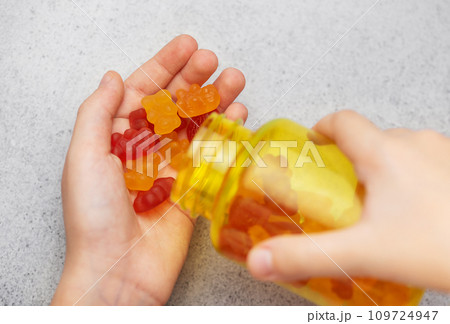 A girl holds a gummy bear vitamines in her hands A girl holds a gummy bear vitamines in her hands 109724947