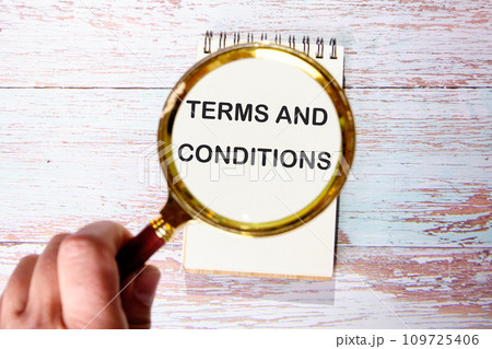 TERMS AND CONDITIONS text seen through magnifying glasses on a notepad TERMS AND CONDITIONS text seen through magnifying glasses on a notepad 109725406