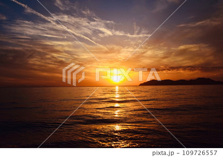虹が出た日の赤みが強い海に沈む夕日 109726557