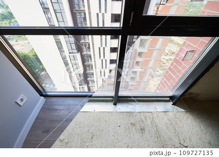 Comparison of living room with large panoramic windows before and after restoration or refurbishment. Residential apartment building behind window glass. Home renovation concept. 109727135