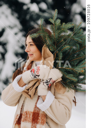 A girl in a winter forest with a bouquet of fir branches. Snowy winter A girl in a winter forest with a bouquet of fir branches. Snowy winter 109728016