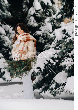 A girl in a winter forest with a bouquet of fir branches. Snowy winter 109728030