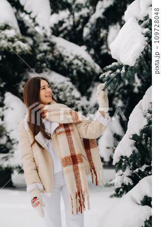Portrait of a girl with long hair in mittens in a winter forest . Snowy winter Portrait of a girl with long hair in mittens in a winter forest . Snowy winter 109728048