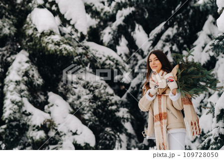 A girl in a winter forest with a bouquet of fir branches. Snowy winter 109728050