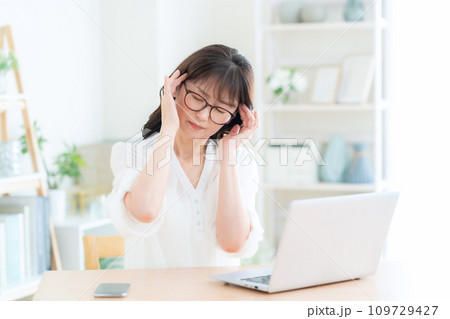 リビングでパソコンを使う疲れ目のミドルの女性 109729427
