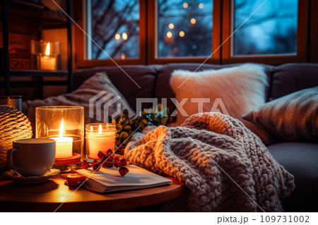 Cozy winter home interior. Cozy living room with candles, book and knitted blanket. Selective Focus 109731002