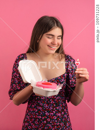 Young girl with bento cake and flower on pink background Young girl with bento cake and flower on pink background 109731228