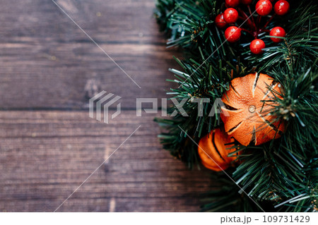 christmas background pine tree with dried tangerines wooden background. The combination of the pine tree, ornaments, and greenery creates a classic and cozy setting. christmas background pine tree with dried tangerines wooden background. The combination of the pine tree, ornaments, and greenery creates a classic and cozy setting. 109731429